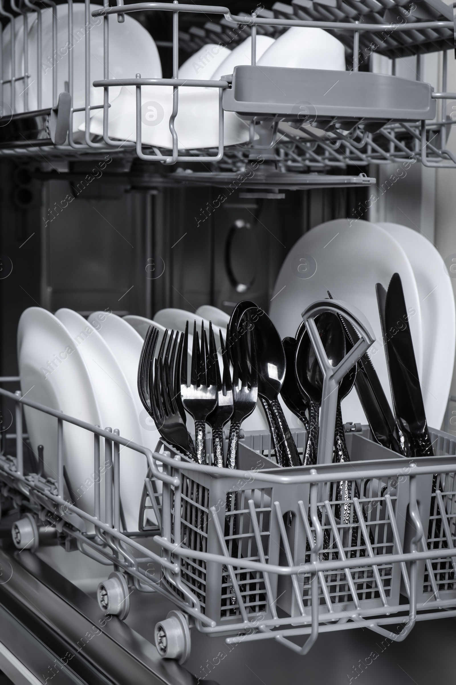 Photo of Open modern dishwasher with clean tableware, closeup