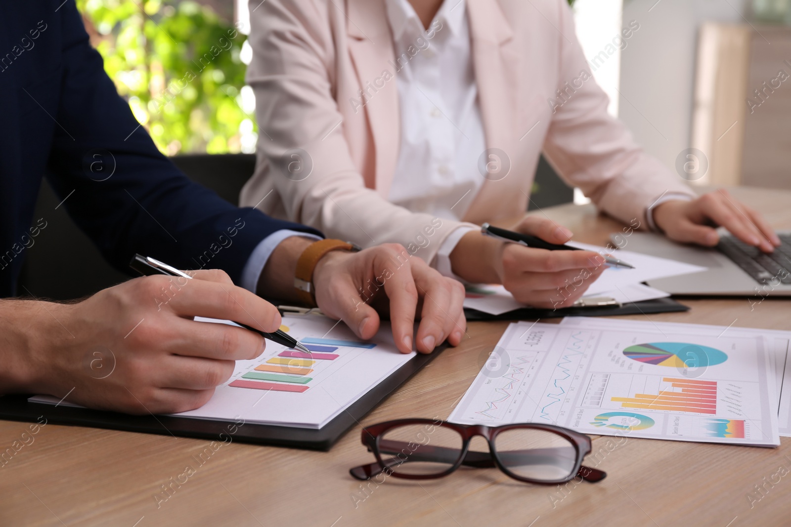 Photo of Business people working with charts and graphs at table in office, closeup. Investment analysis