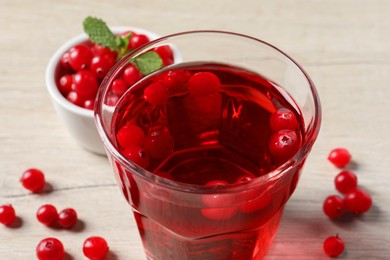 Photo of Tasty refreshing cranberry juice and fresh berries on light wooden table, closeup