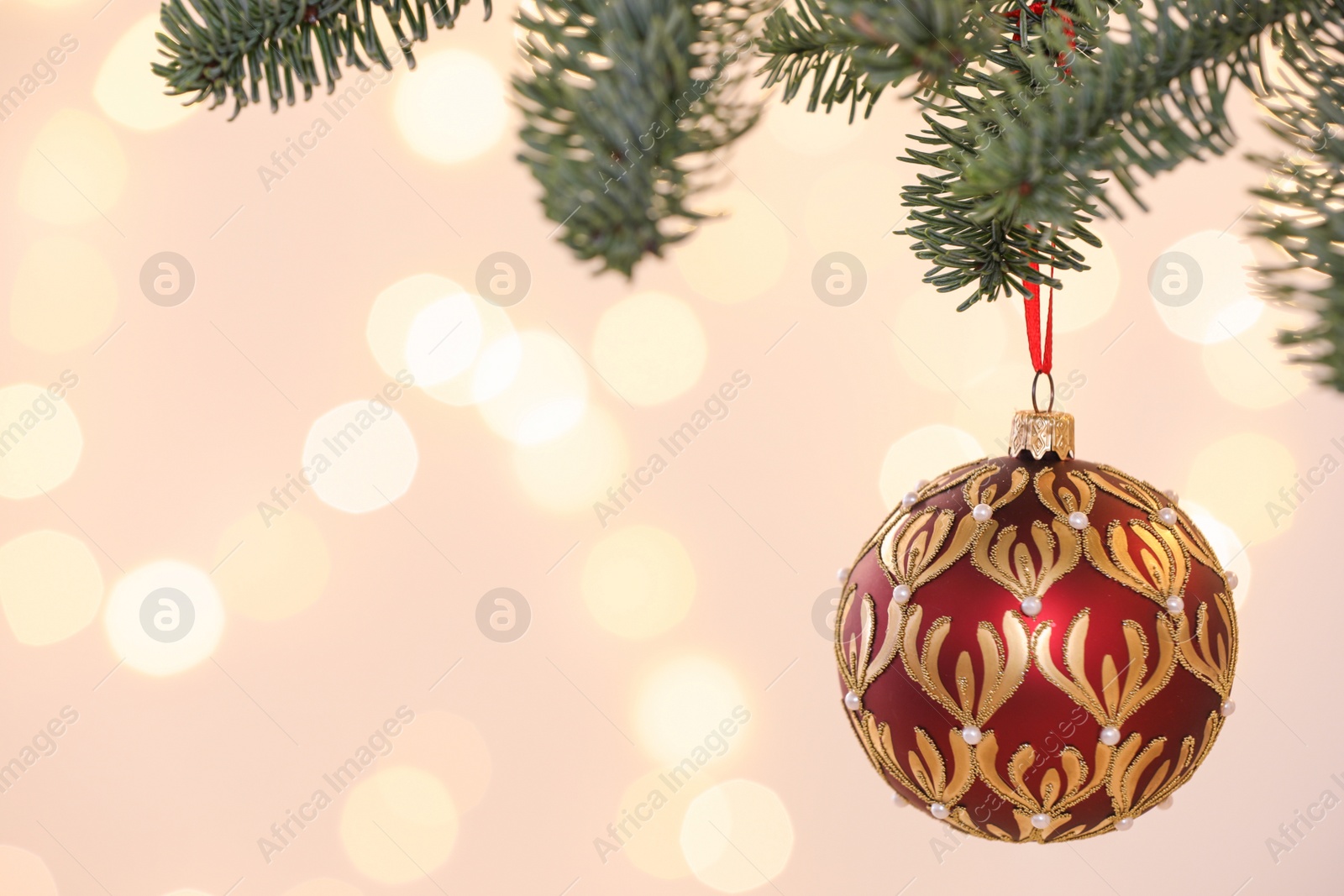 Photo of Beautiful holiday bauble hanging on Christmas tree against blurred lights, closeup. Space for text