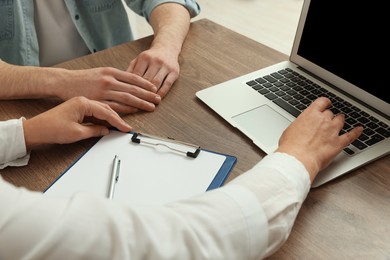 Professional doctor working with patient at wooden table, closeup