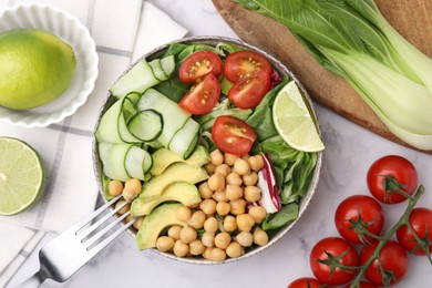 Photo of Tasty salad with chickpeas and vegetables served on white marble table, flat lay