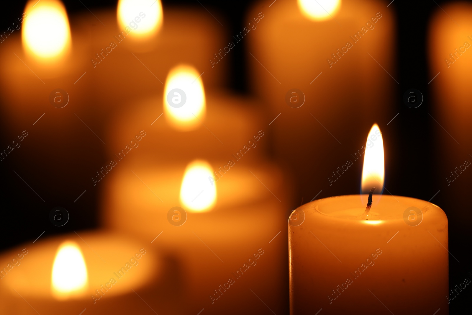 Photo of Burning candles on black background, closeup. Space for text