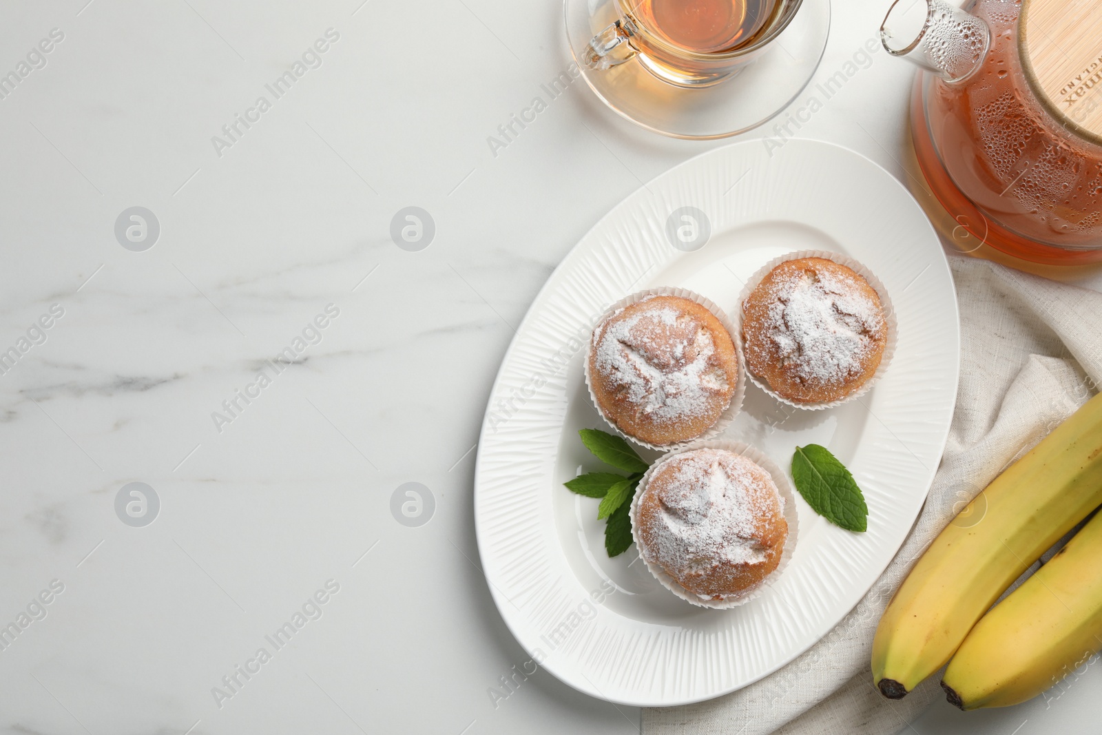Photo of Flat lay composition with homemade banana muffins and tea on white marble table. Space for text