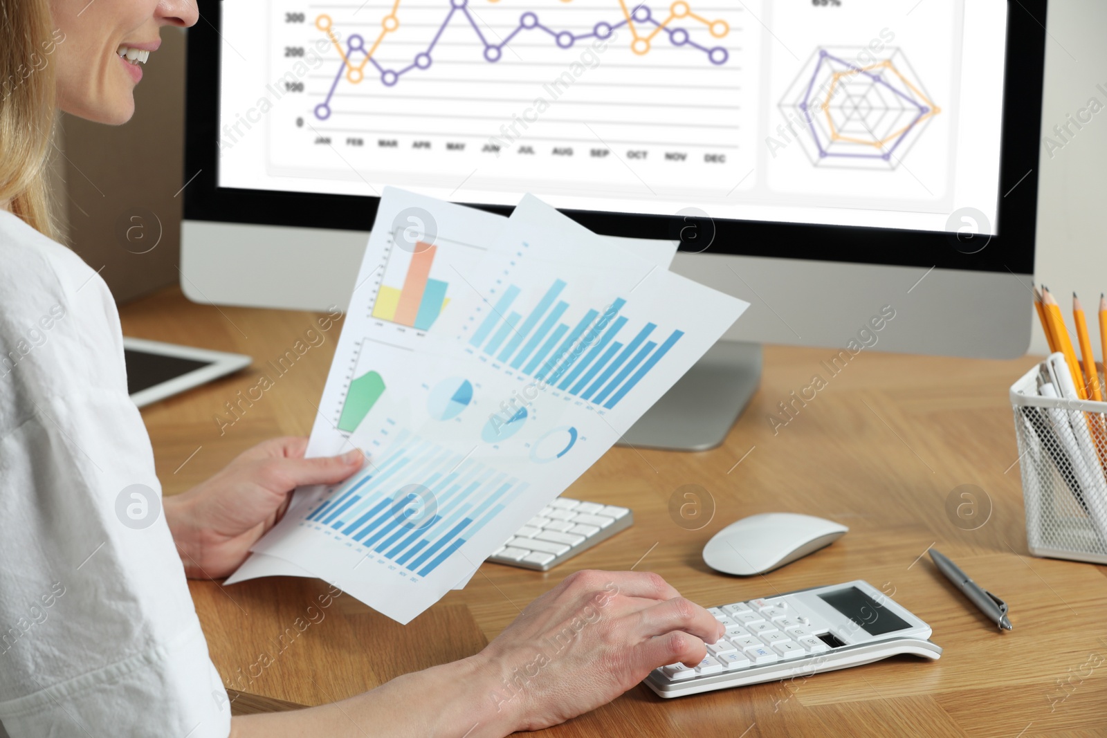 Photo of Professional accountant using calculator at wooden desk in office, closeup