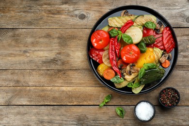 Photo of Delicious grilled vegetables served on wooden table, flat lay. Space for text