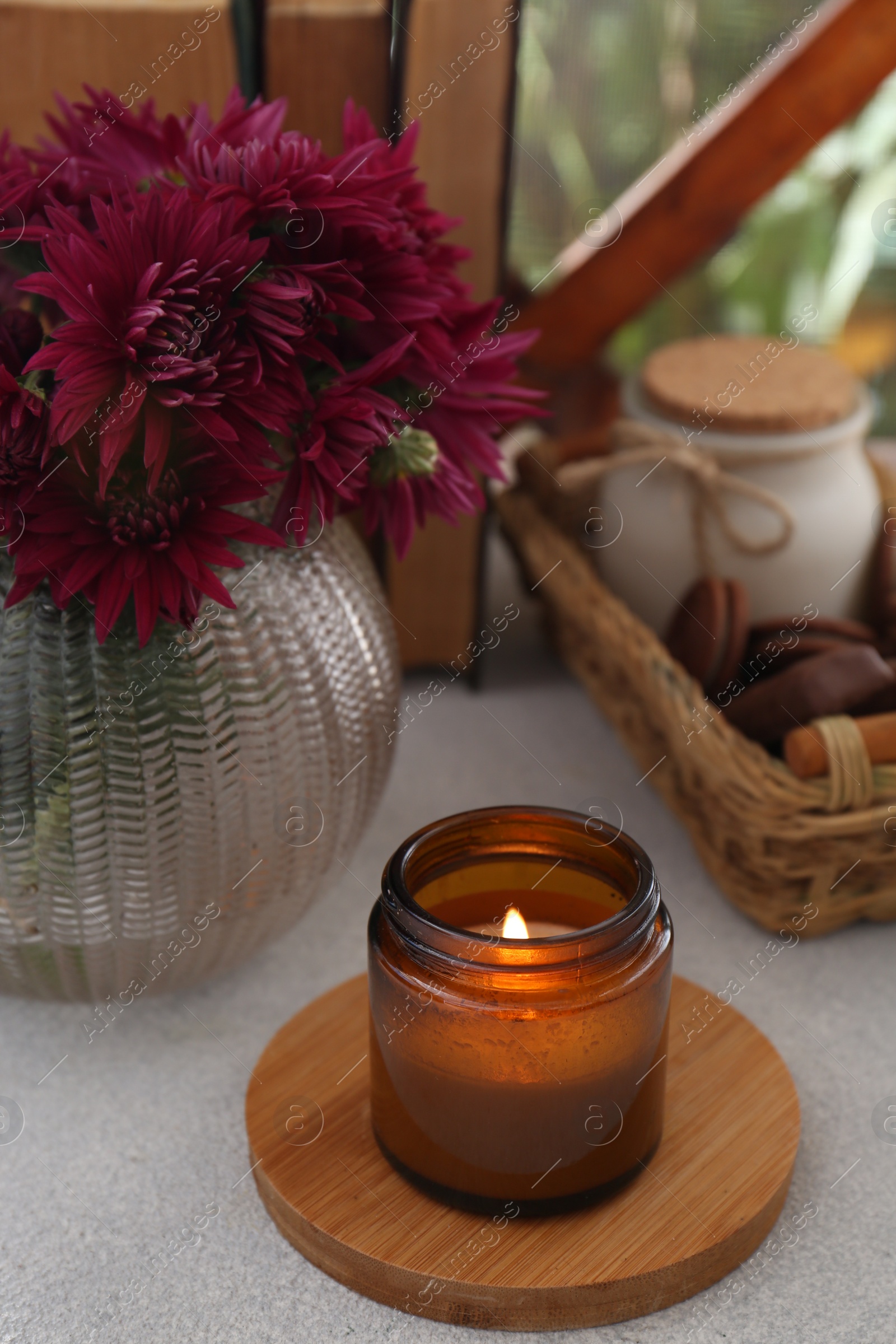 Photo of Beautiful pink chrysanthemum flowers, burning candle and sweet chocolate treats on light grey table