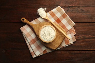 Photo of Baking powder in bowl and spoon on wooden table, top view