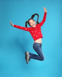 Portrait of little girl jumping on color background