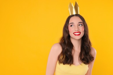 Photo of Beautiful young woman with princess crown on yellow background, space for text