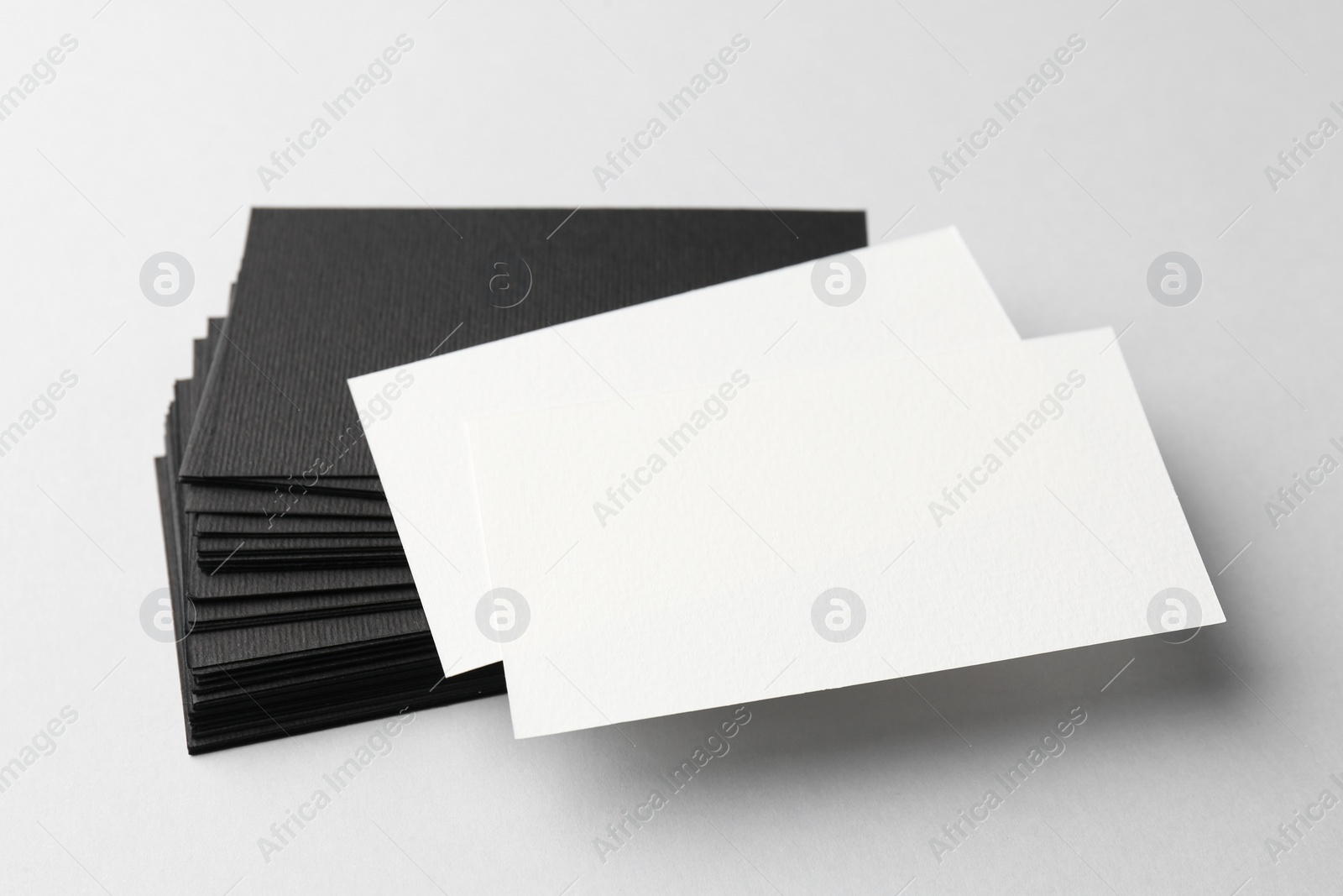 Photo of Blank black and white business cards on light background, closeup. Mockup for design