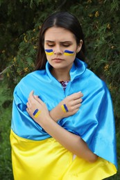 Photo of Sad young woman with Ukrainian flag outdoors