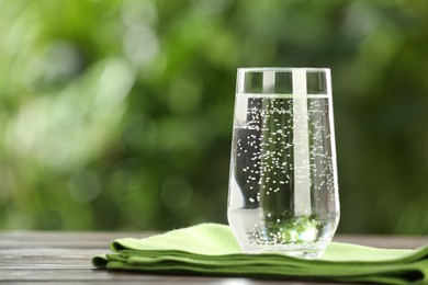 Glass of fresh water on wooden table outdoors. Space for text