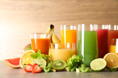 Glasses with different juices and fresh fruits on table