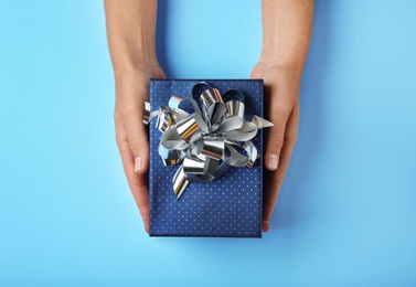 Photo of Woman holding beautiful gift box on blue background, top view