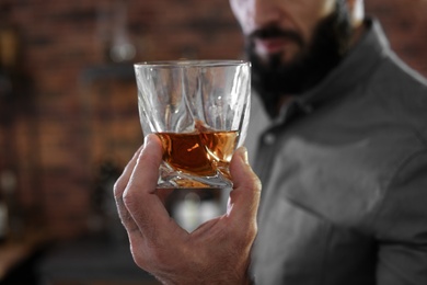 Man with glass of whiskey indoors, closeup