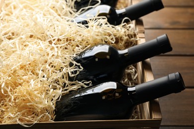 Photo of Crates with bottles of wine on wooden background, closeup