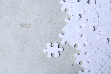 Blank white puzzle pieces on light grey stone background, flat lay. Space for text