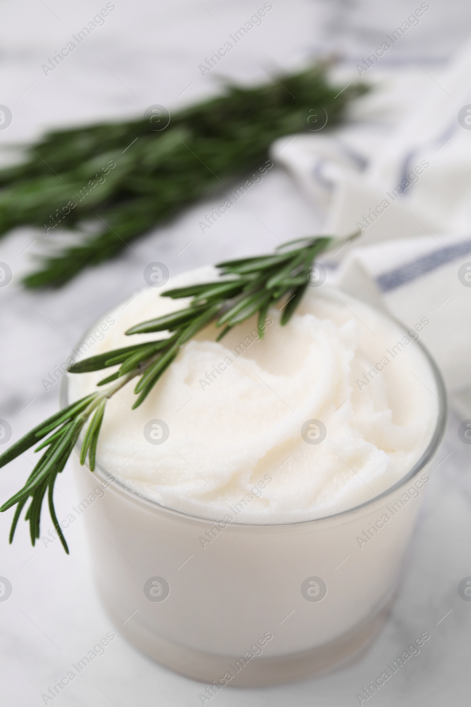 Photo of Delicious pork lard with rosemary in glass on white marble table, closeup