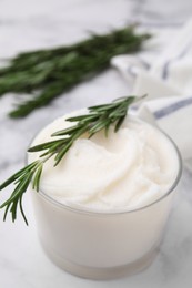 Delicious pork lard with rosemary in glass on white marble table, closeup