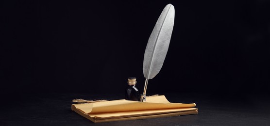 Image of Quill, bottle of ink and old paper on black table. Banner design