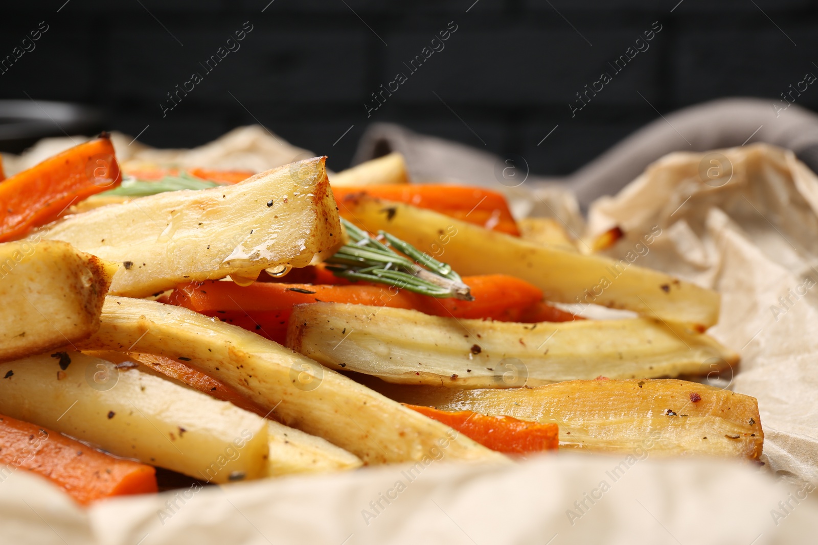 Photo of Tasty baked parsnip and bell pepper on parchment, closeup