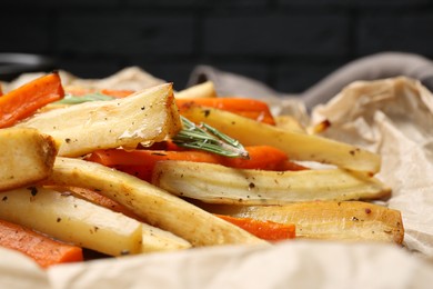 Tasty baked parsnip and bell pepper on parchment, closeup