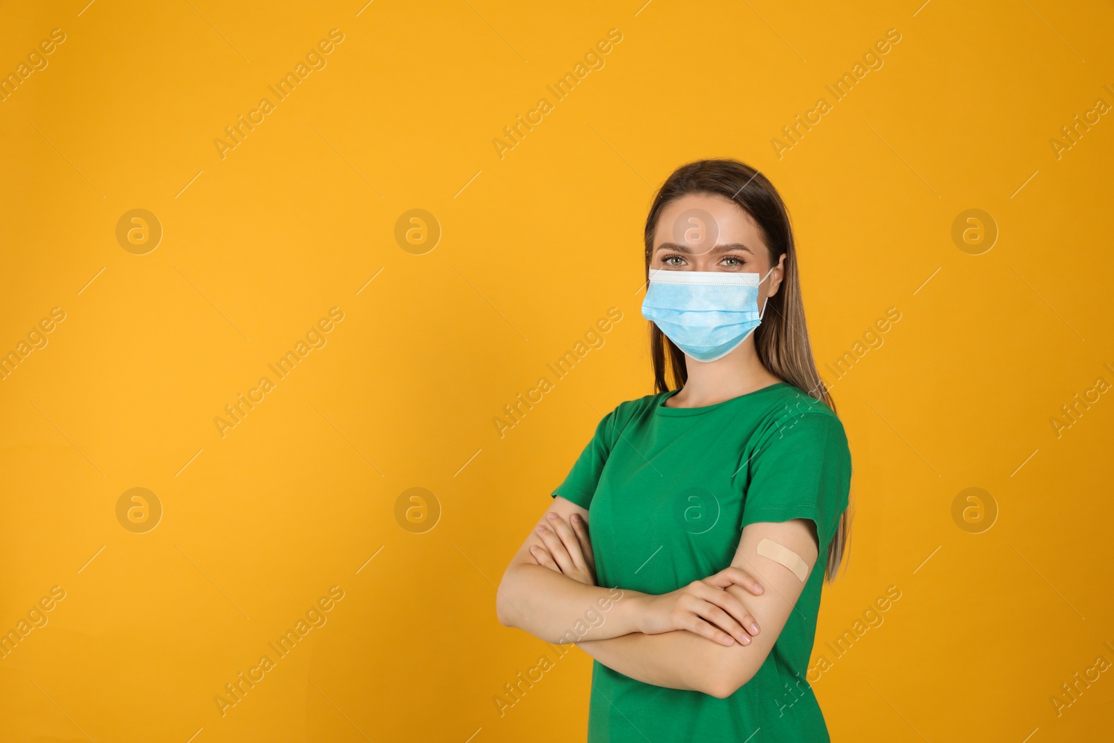 Photo of Vaccinated woman with protective mask and medical plaster on her arm against yellow background. Space for text