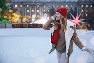 Image of Happy young woman skating at outdoor ice rink