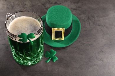 Photo of St. Patrick's day celebration. Green beer, leprechaun hat and decorative clover leaves on grey table. Space for text