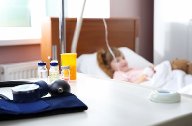 Photo of Table with medicaments and little child in hospital bed
