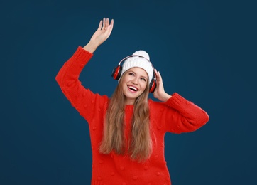 Young woman listening to music with headphones on dark blue background