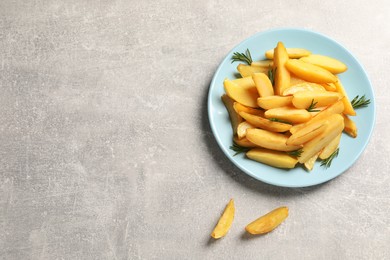 Photo of Plate with tasty baked potato wedges and rosemary on grey table, flat lay. Space for text