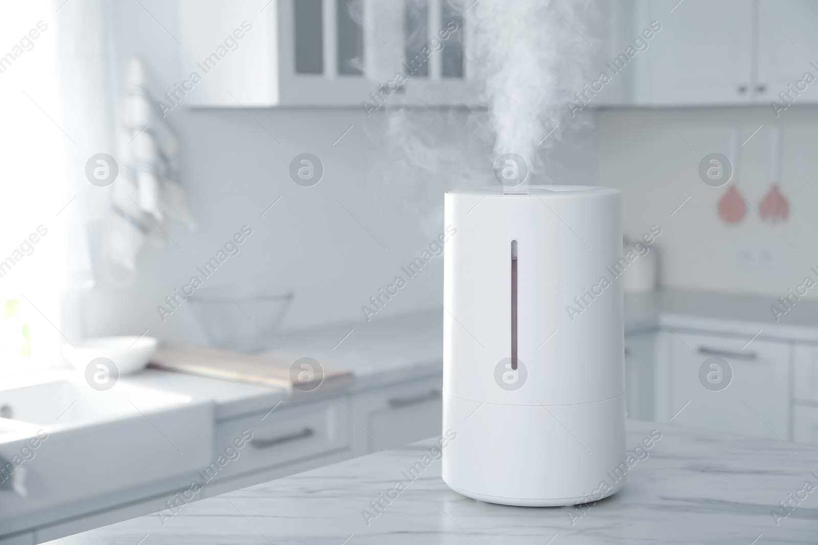 Photo of Modern air humidifier on table in kitchen. Space for text