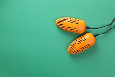 Photo of Modern electric shoe dryer on green background, top view. Space for text