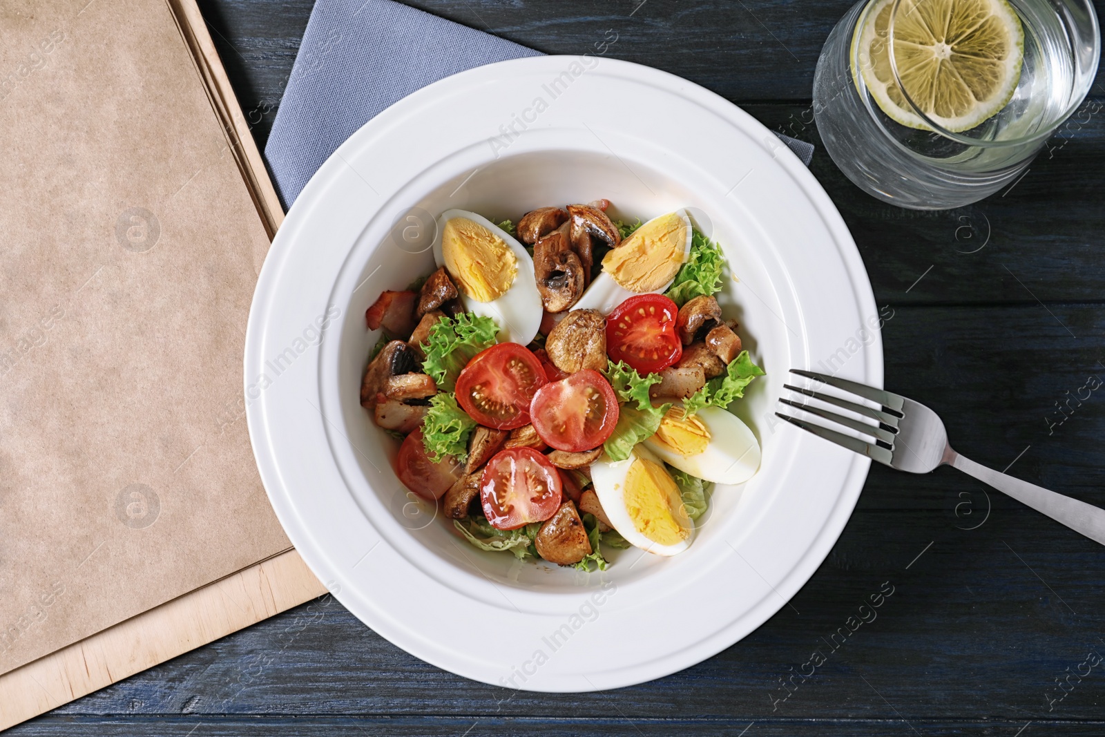 Photo of Plate with delicious fresh salad and menu on table, top view