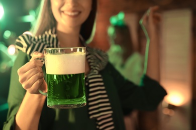 Photo of Woman with beer celebrating St Patrick's day in pub, focus on hand