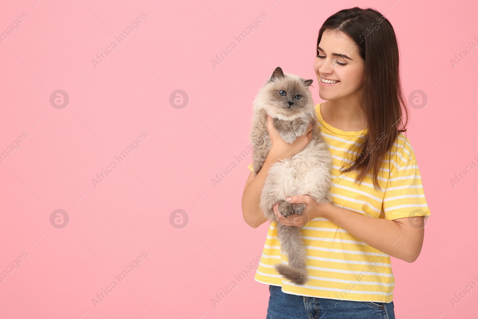 Photo of Happy woman with her cute cat on pink background, space for text