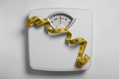 Weight loss concept. Scales and measuring tape on white background, top view