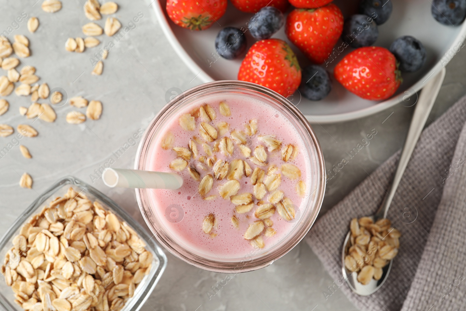 Photo of Jar of tasty berry oatmeal smoothie on grey table, flat lay