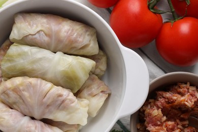 Uncooked stuffed cabbage rolls and ingredients on table, flat lay