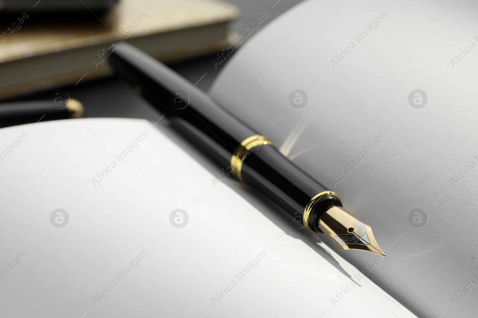 Photo of Stylish black fountain pen on open notebook, closeup