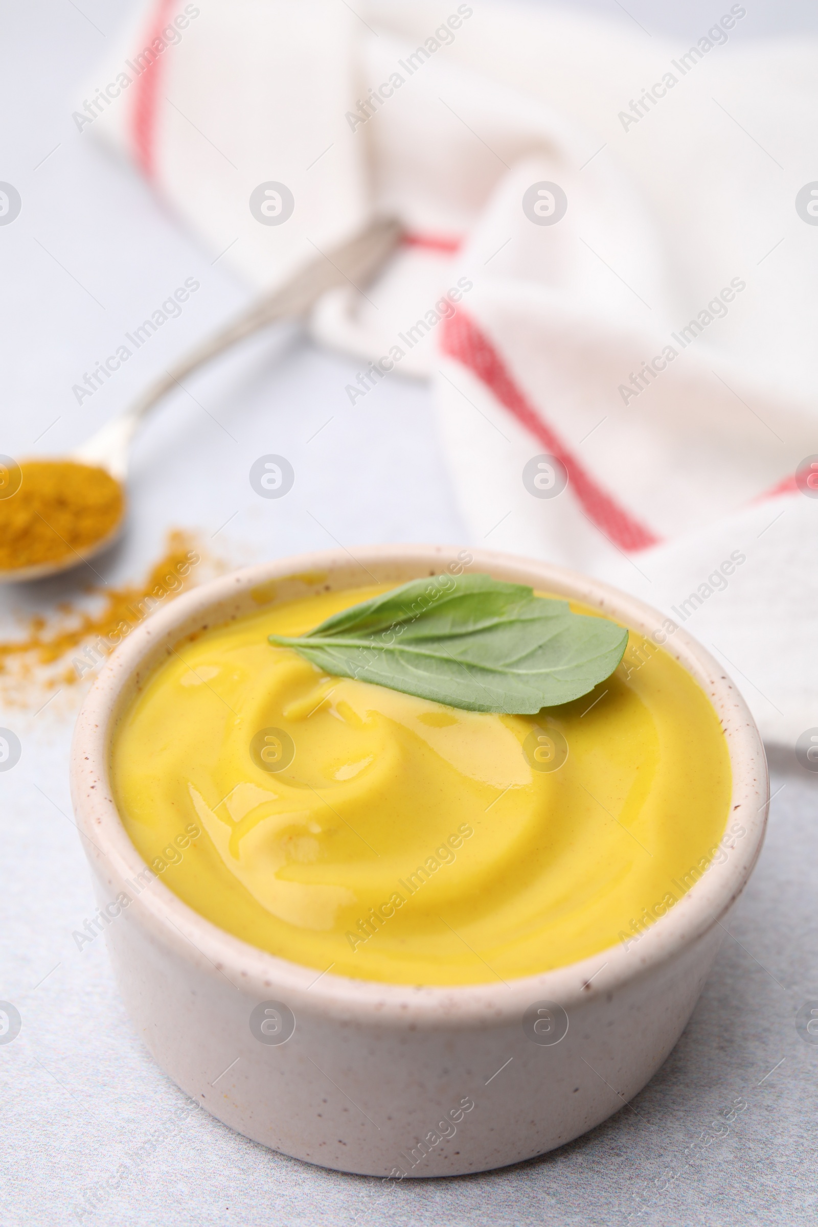 Photo of Tasty curry sauce, powder and basil leaf on light table