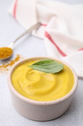 Photo of Tasty curry sauce, powder and basil leaf on light table