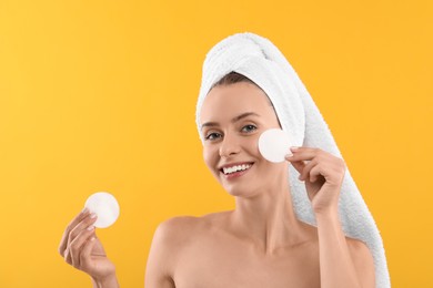 Removing makeup. Smiling woman with cotton pads on yellow background