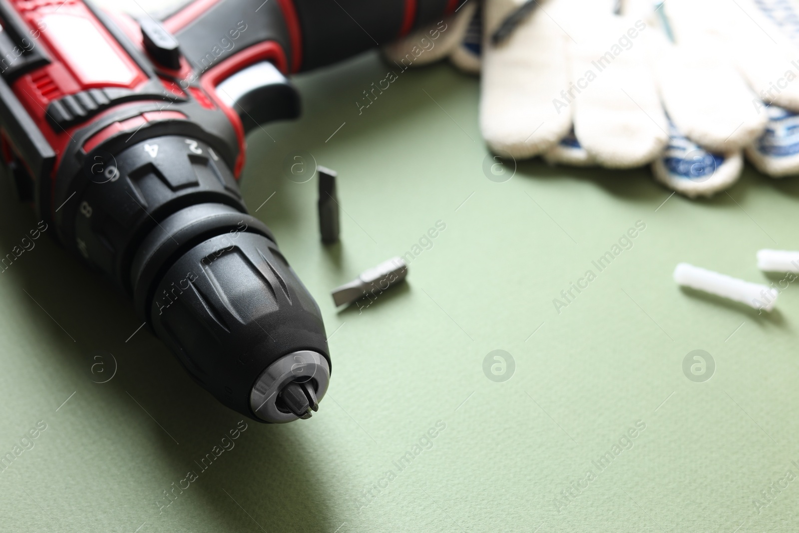 Photo of Electric screwdriver on pale green background, closeup. Space for text