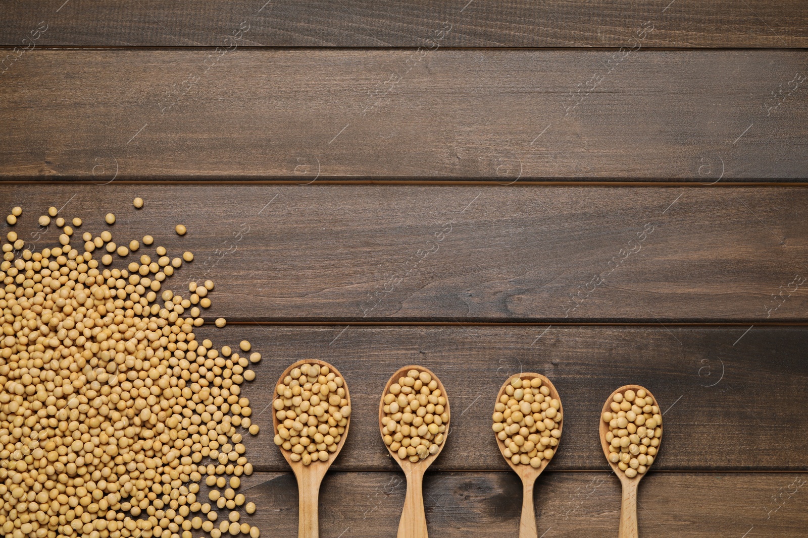 Photo of Soy and spoons on wooden table, flat lay. Space for text