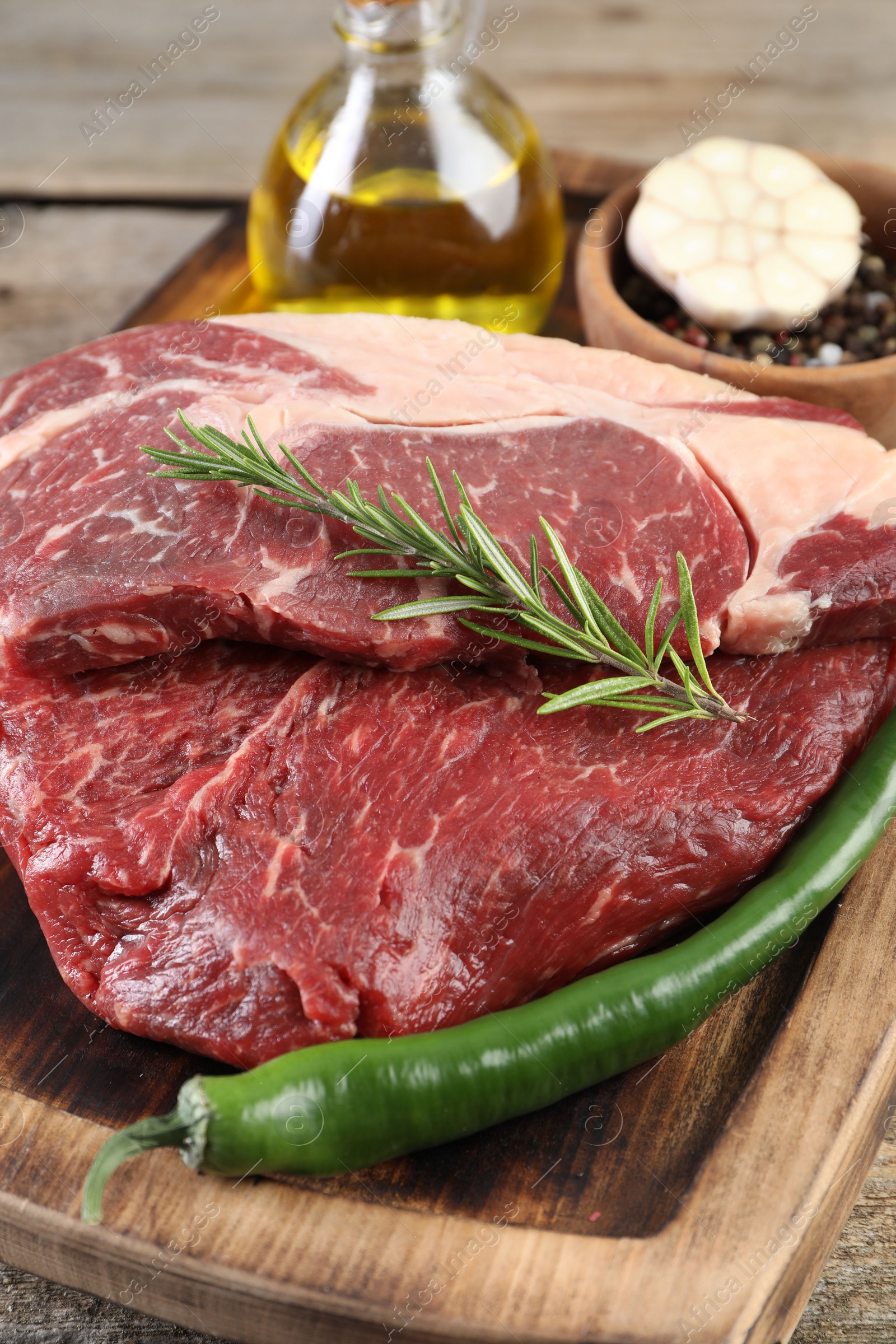 Photo of Fresh raw beef cut with spices on wooden table, closeup