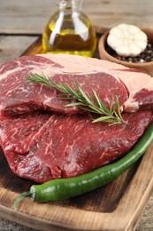 Photo of Fresh raw beef cut with spices on wooden table, closeup