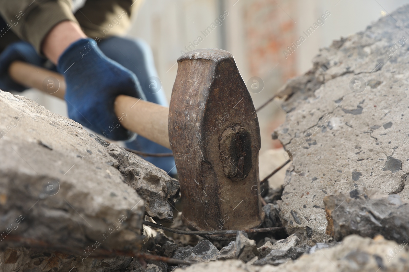 Photo of Man breaking stones with sledgehammer outdoors, closeup